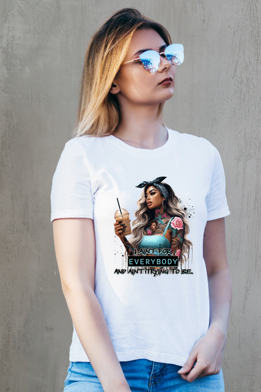 Woman wearing a white t-shirt with a graphic design and sunglasses against a gray wall.