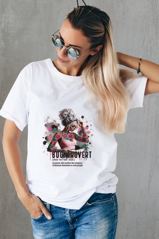 Woman wearing a white t-shirt with a graphic design and text, standing against a gray wall.