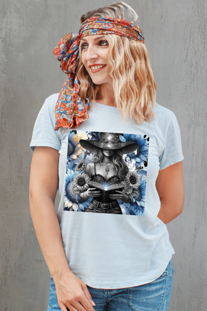 Woman wearing a light blue t-shirt with a graphic design, standing against a gray concrete wall.