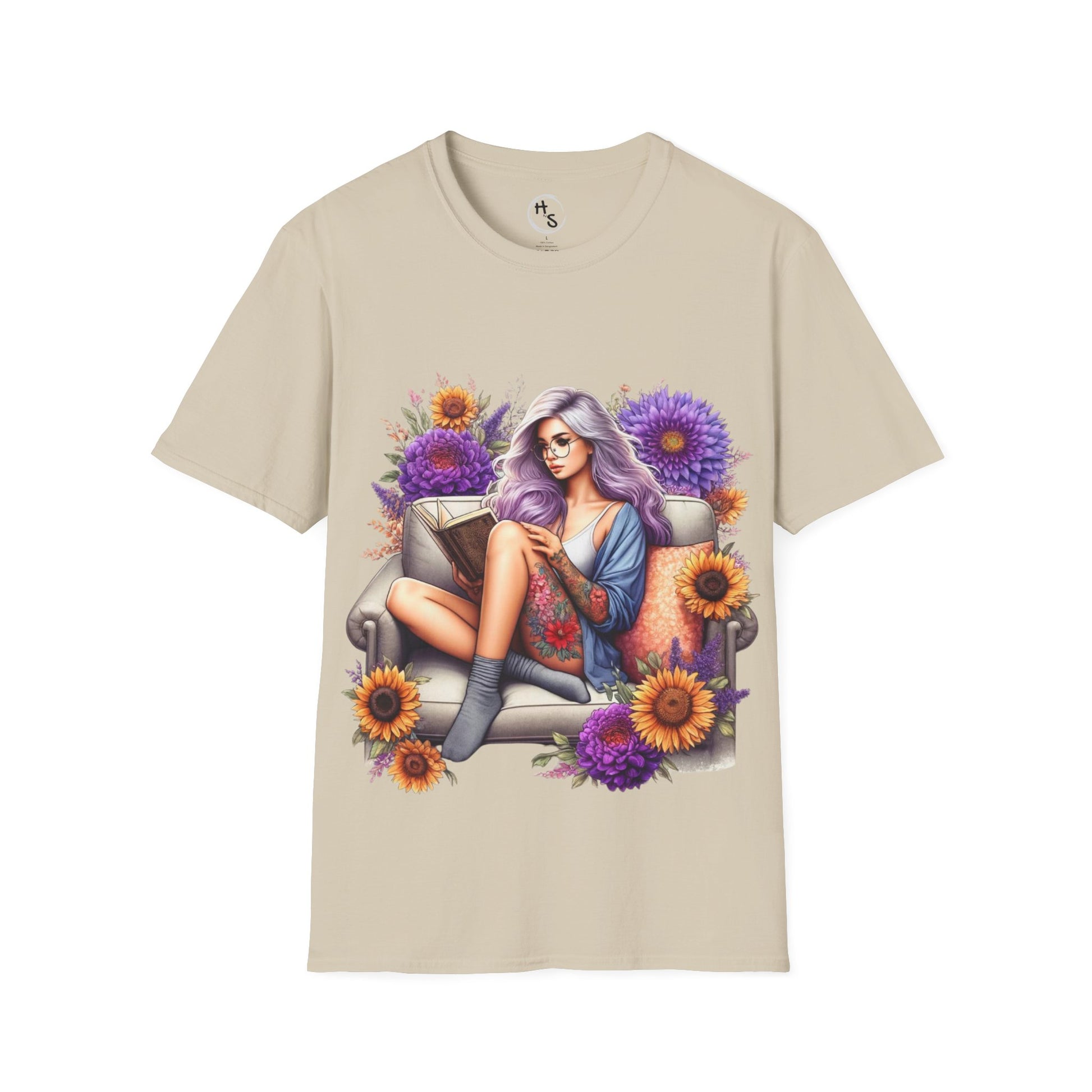 Beige t-shirt with a graphic of a woman with purple hair sitting on a chair surrounded by flowers on a white background.
