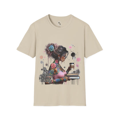 Beige t-shirt with a graphic design of a woman with tattoos and flowers, holding a coffee cup and book, on a beige background.