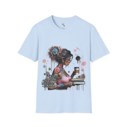 Light blue t-shirt with a graphic design of a woman with tattoos and flowers, holding a coffee cup and book, on a light blue background.