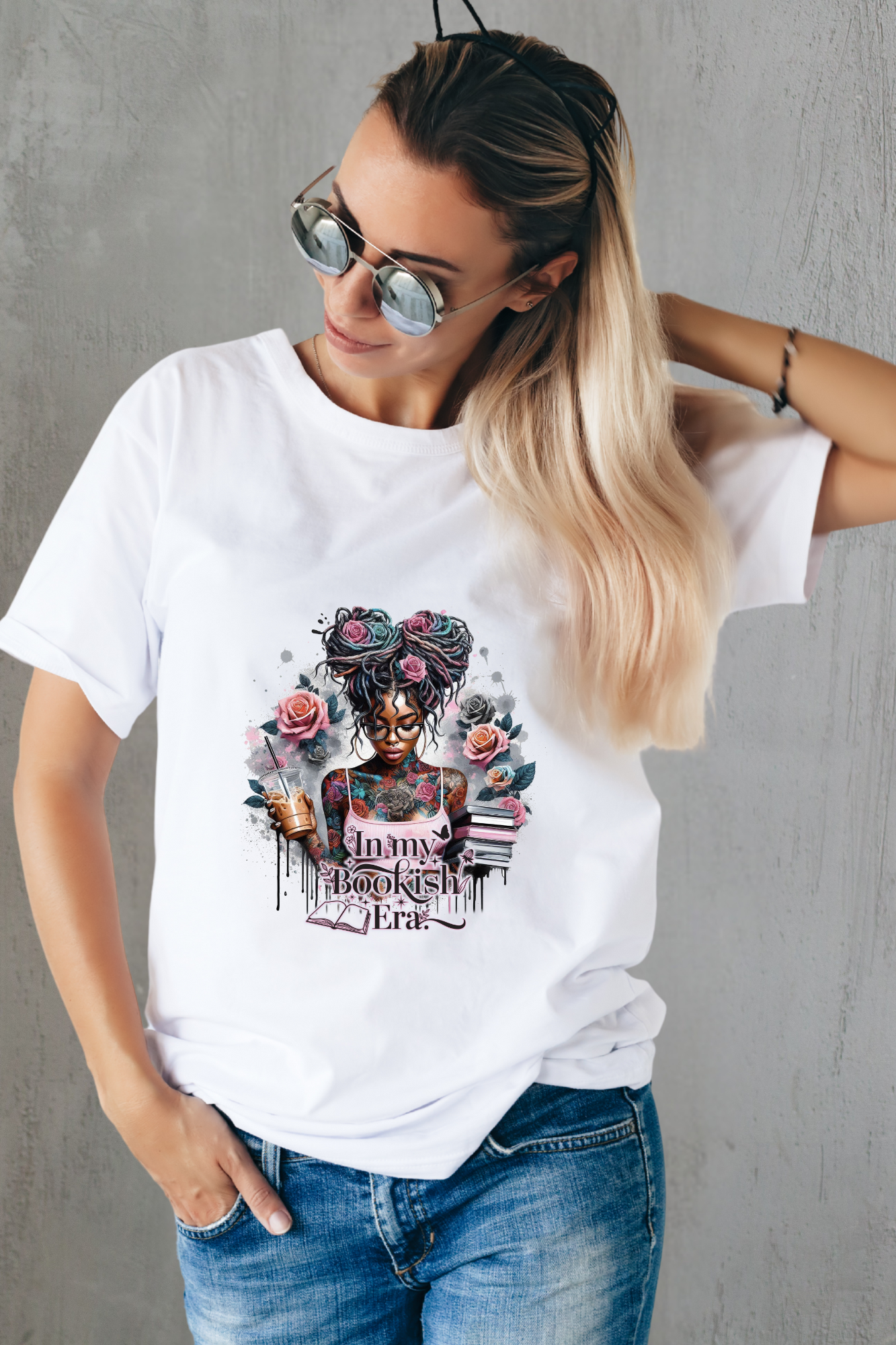 Woman wearing a white t-shirt with a graphic design and text, standing against a gray wall.