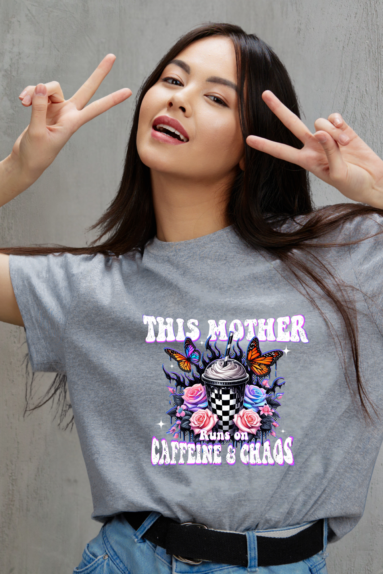 Woman wearing a gray t-shirt with a colorful graphic and text, making peace signs.