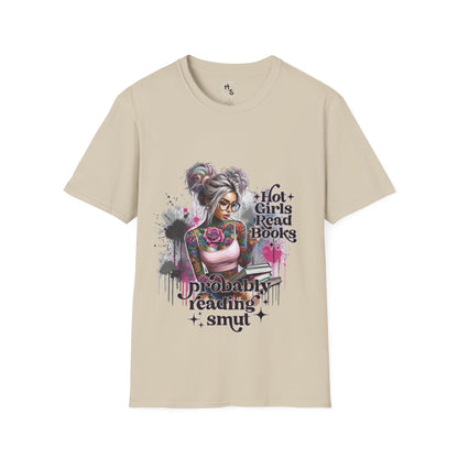 Beige T-shirt with a colorful graphic of a tattooed girl holding books, sitting casually against a gray wall.