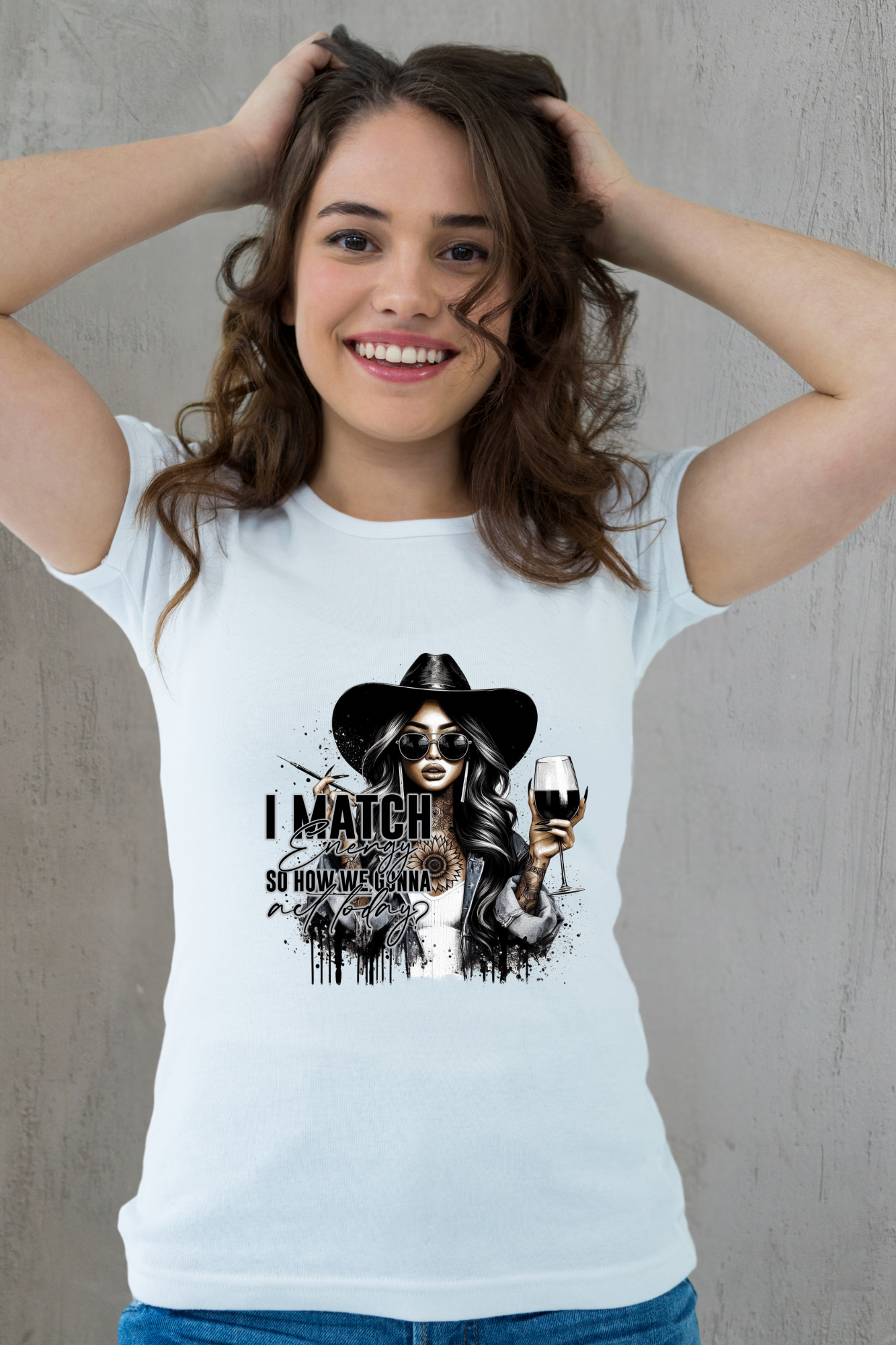 Woman wearing a white t-shirt with a graphic design of a woman in a hat and sunglasses, holding a wine glass, with text on a plain background.