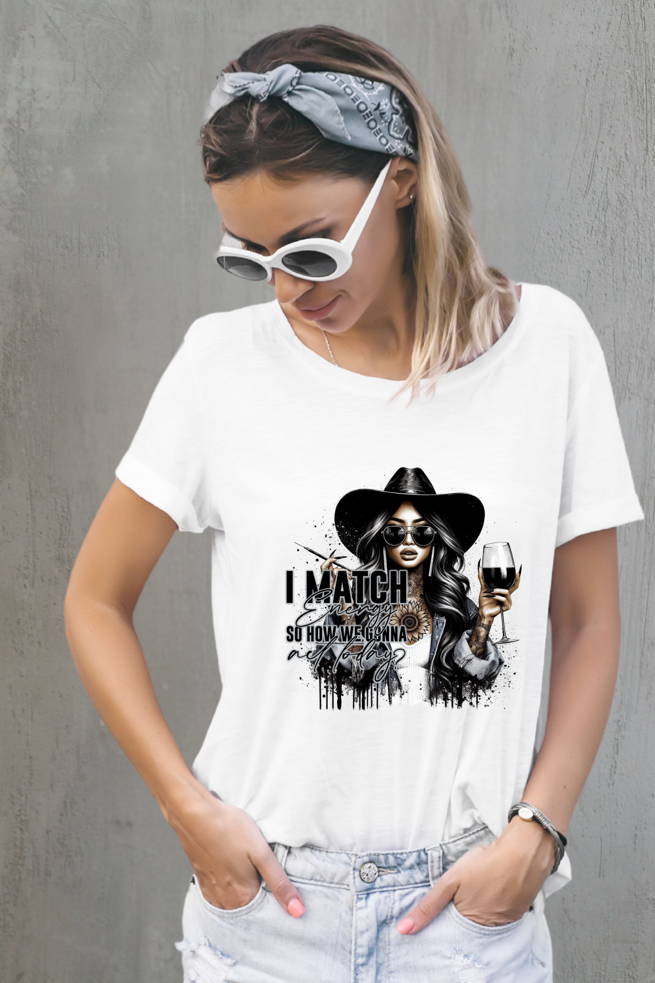 Woman wearing a white t-shirt with a graphic design and sunglasses against a gray background