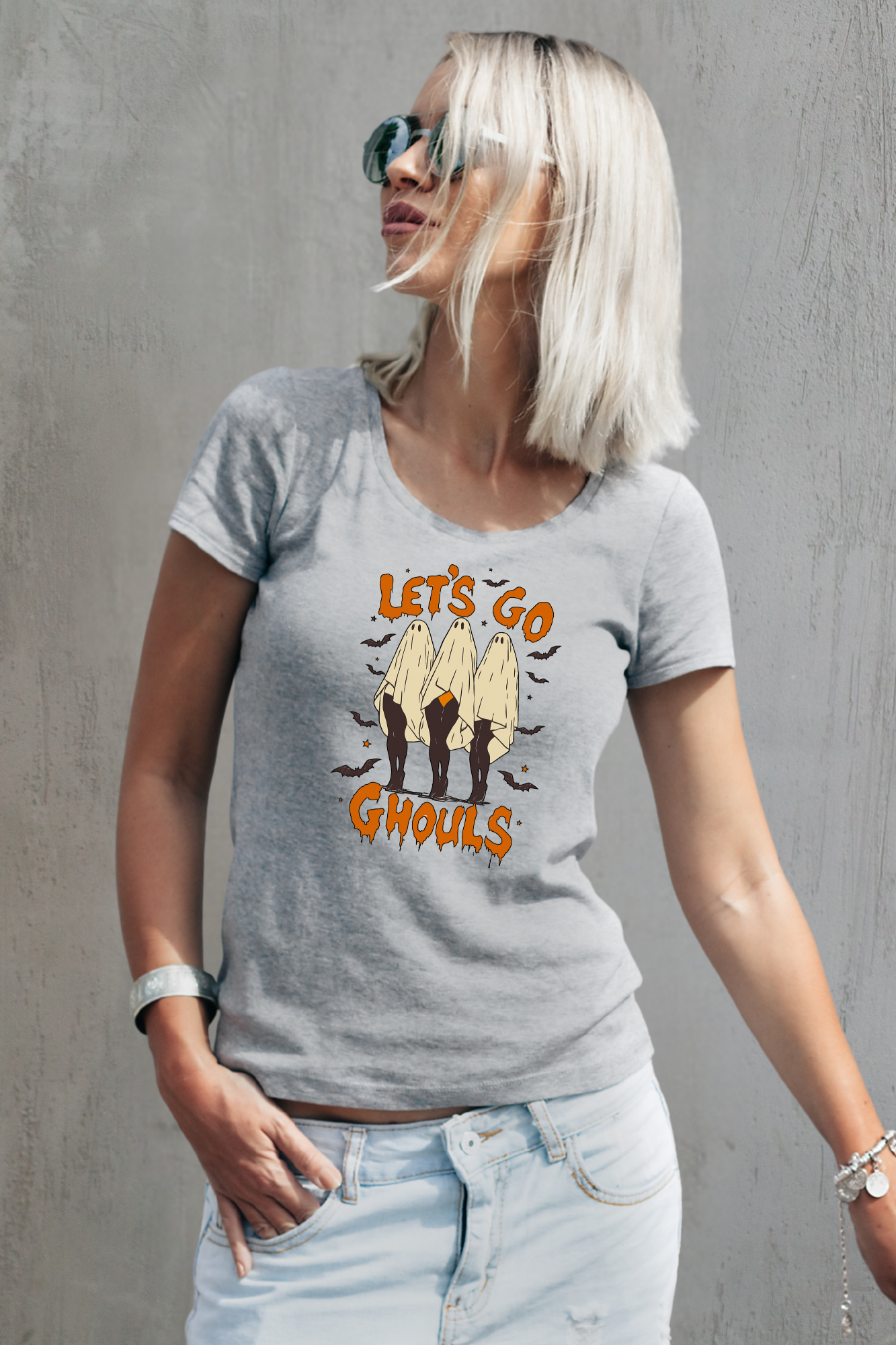 Person wearing a gray t-shirt with 'Let's Go Ghouls' graphic design against a gray background