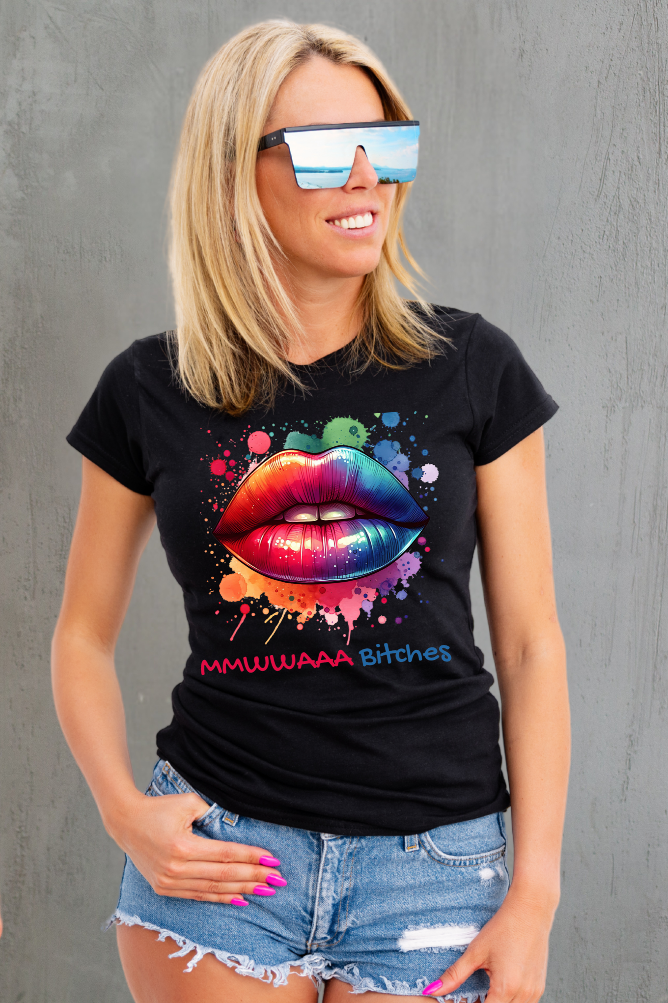 Woman wearing a black t-shirt with colorful lips design and denim shorts against a gray background