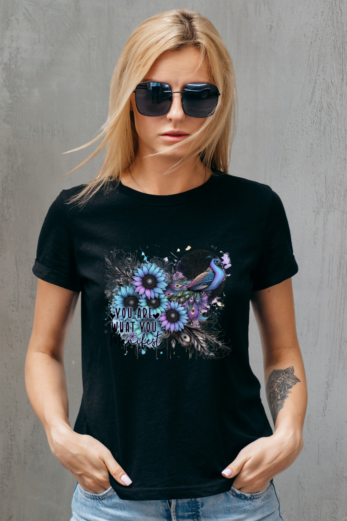 Woman wearing a black t-shirt with floral and peacock design against a gray background