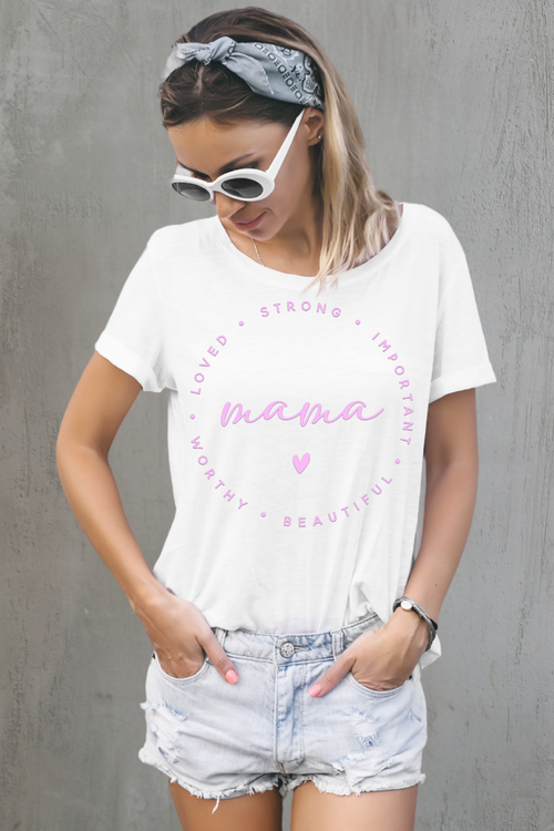 Woman wearing a white t-shirt with pink text and denim shorts against a gray wall.