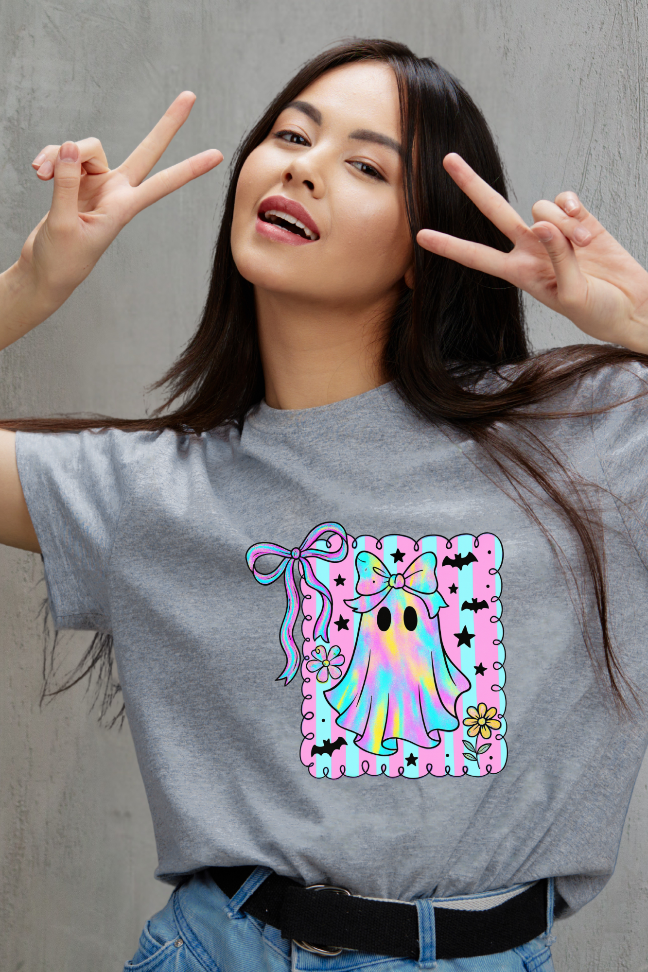 Woman wearing a gray t-shirt with a colorful graphic design, making peace signs.