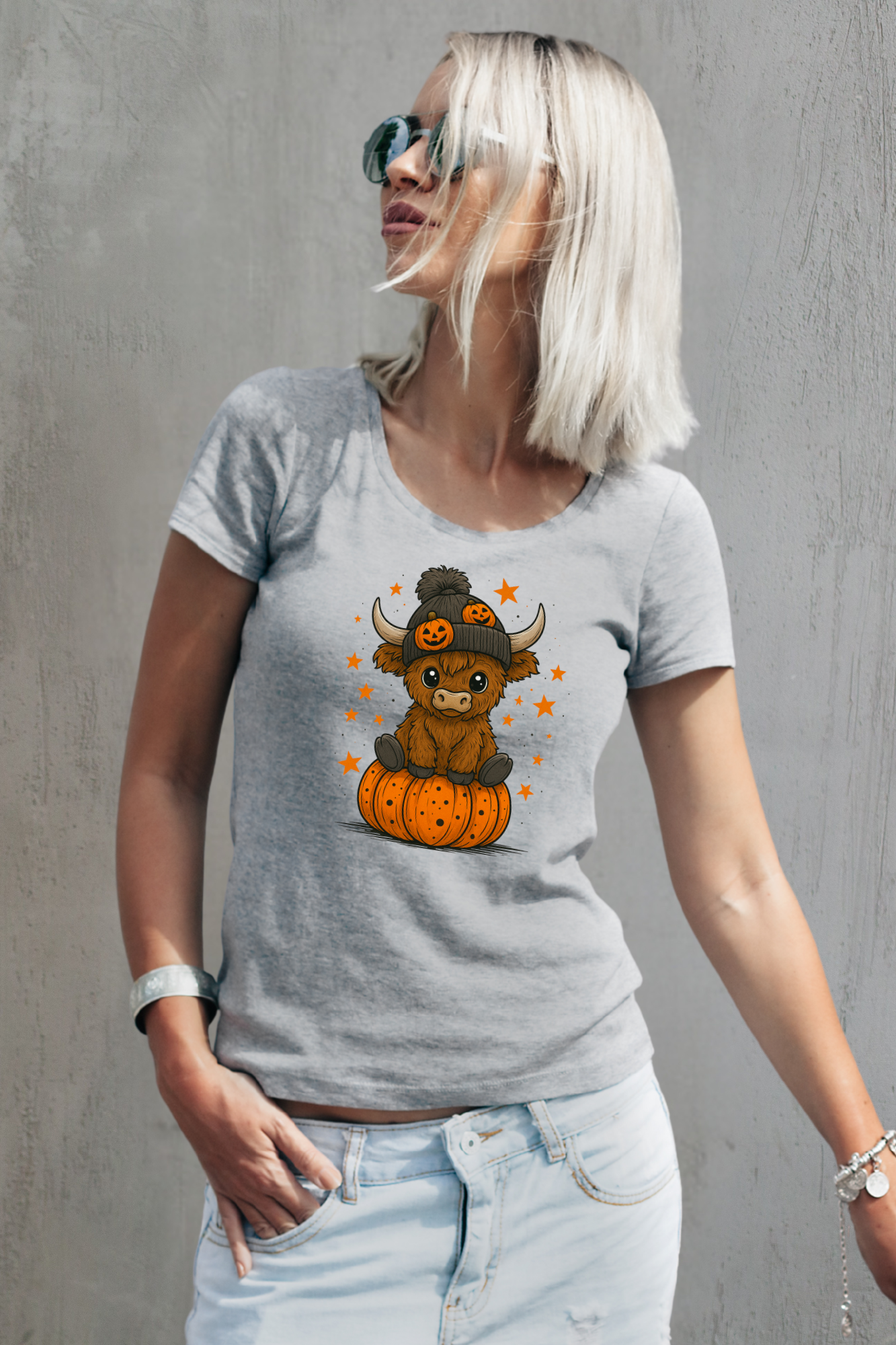 Woman wearing a gray t-shirt with a cow on a pumpkin graphic against a gray background