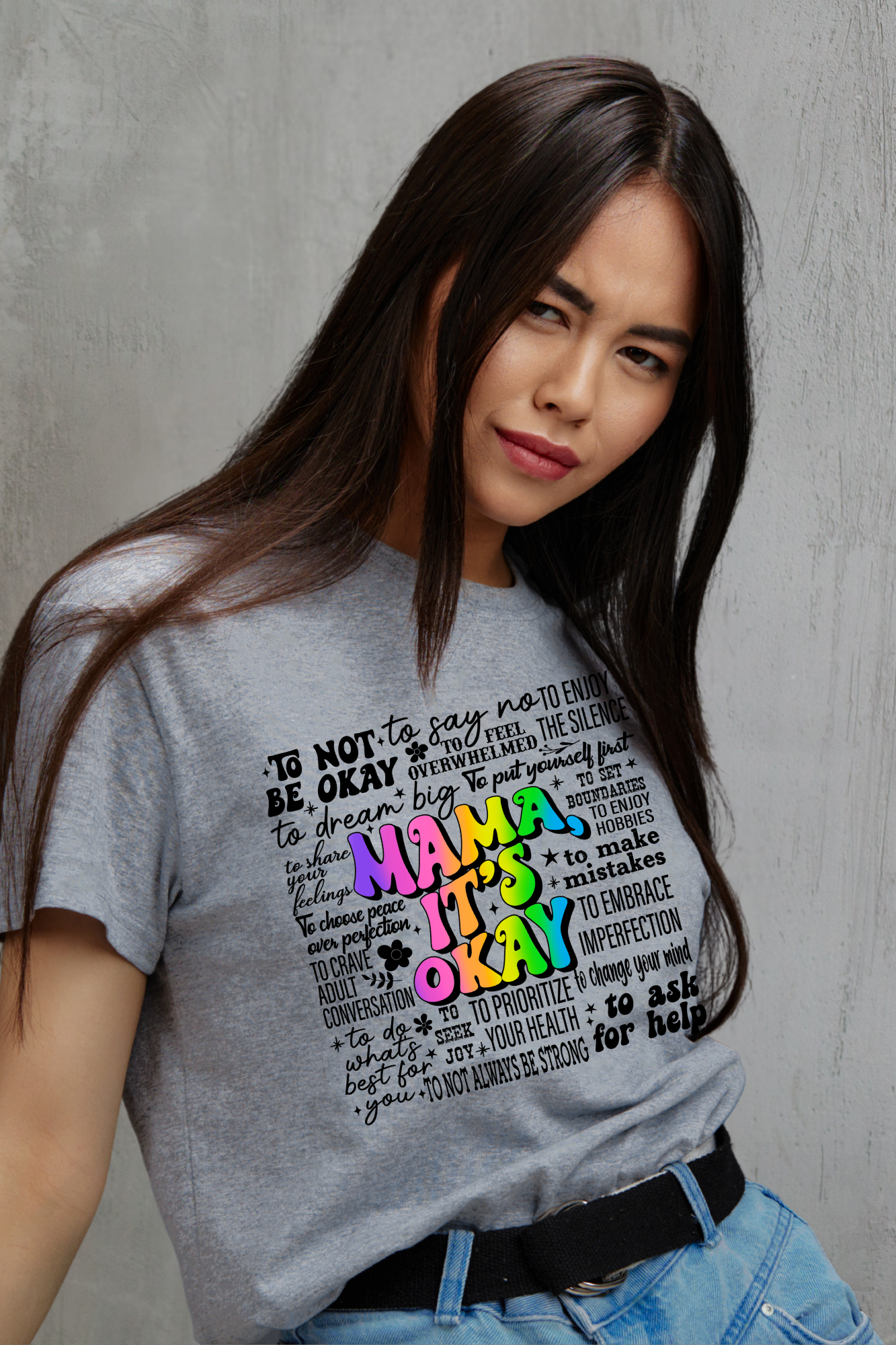 Woman wearing a gray t-shirt with colorful text design against a grey background