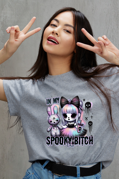 Woman wearing a gray t-shirt with a hallloween graphic design and text, making peace signs.