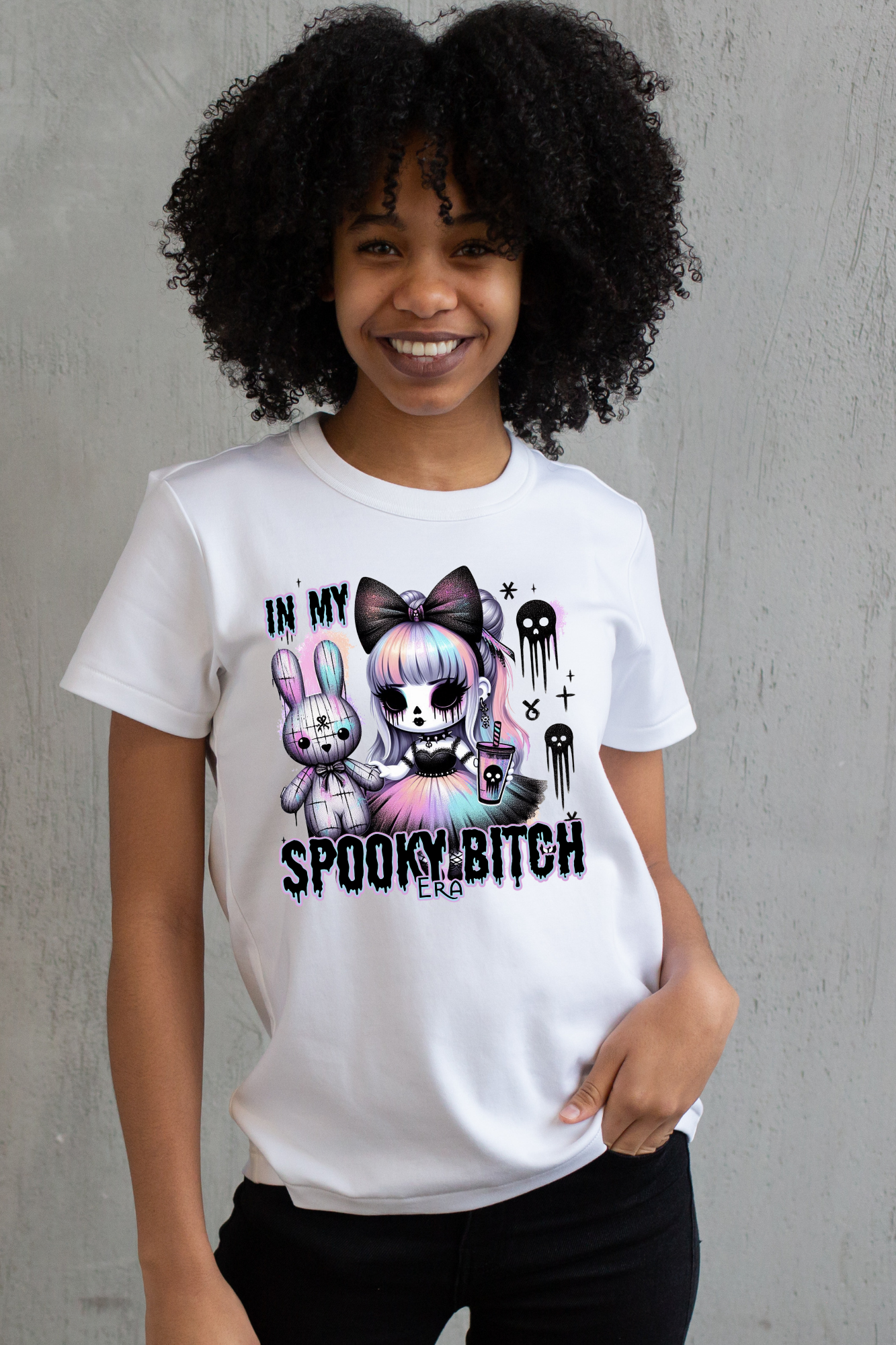 Person wearing a white t-shirt with a spooky graphic design and text, standing against a white background