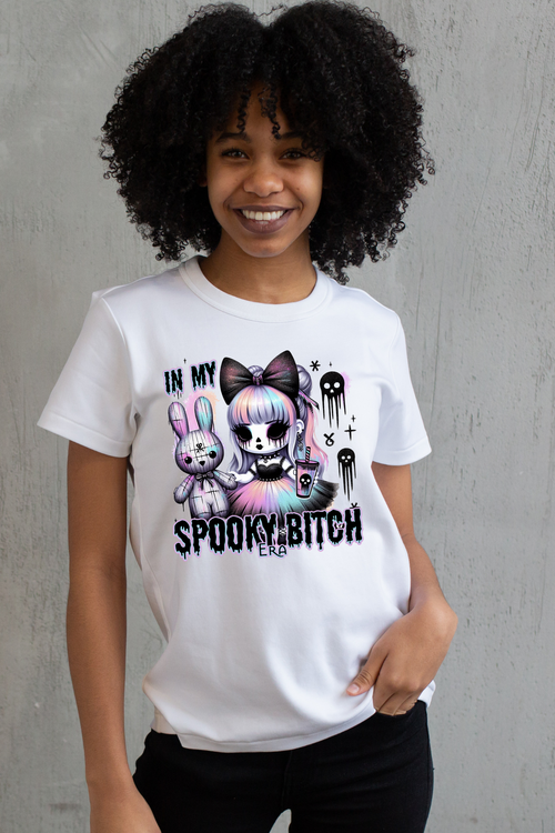 Person wearing a white t-shirt with a spooky graphic design and text, standing against a white background